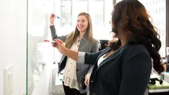 Zwei duale Studenten der KOMSA arbeiten auf einem Whiteboard an der Wand