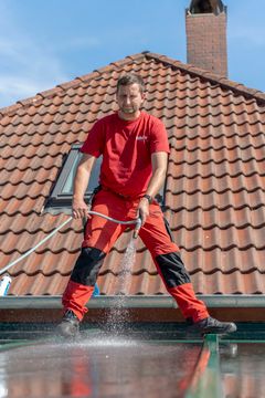 Ein Mitarbeiter von aktiv sprüht Wasser auf einen Wintergarten