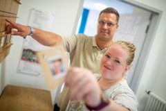 Frau und Mann stecken den Dienstplan und blicken in die Kamera