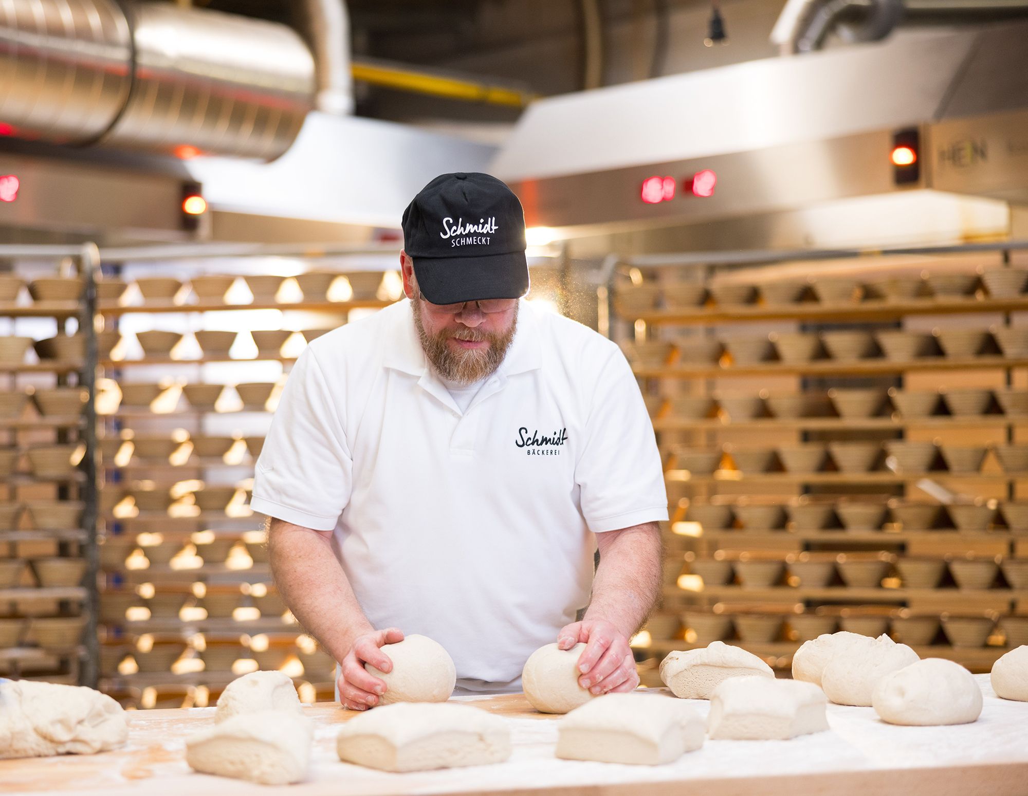 Bäcker der Bäckerei Schmidt formt Teiglinge in der Backstube.