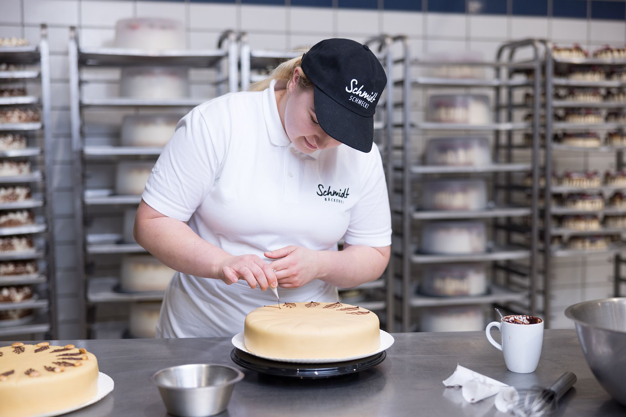 Konditorin der Bäckerei Schmidt verziert eine Torte in der Produktion.