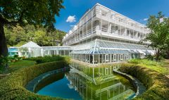 Modernes Gebäude mit Glasfassade, Teich und viel Grün drumherum