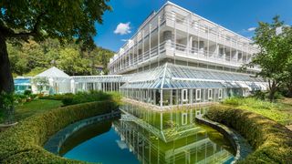 Modernes Gebäude mit Glasfassade, Teich und viel Grün drumherum