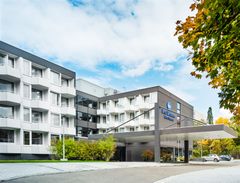 modernes Gebäude mit Balkonen und Bäumen davor