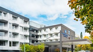 modernes Gebäude mit Balkonen und Bäumen davor