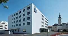 Best Western Hotel  Tulln​, Modernes weißes Gebäude mit Kirche im Hintergrund
