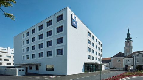 Best Western Hotel  Tulln​, Modernes weißes Gebäude mit Kirche im Hintergrund