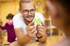 Ein Mann mit Brille hält in seinen Händen den Buchstaben M