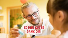 Ein Mann mit Brille lächelt ein Mädchen an. So viel Gutes dank dir.