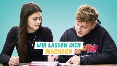 Eine junge Frau und ein junger Mann schauen gemeinsam in ein Buch. Wir lassen dich wachsen. 