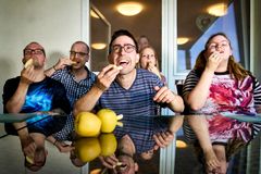 Drei Männer und zwei Frauen sitzen nebeneinander und essen jeder ein Stück Apfel. Sie lachen und gucken in die Kamera. Beziehungen gibt´s bei uns gratis dazu!
