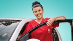 Mitarbeiterin der Caritas steht an ihrem Dienstfahrzeug