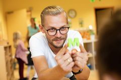 Ein Mann mit Brille hält in seinen Händen den Buchstaben M