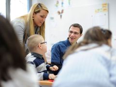 Eine Frau, ein junger Mann und ein kleiner Junge sitzen in der Schule und unterhalten sich