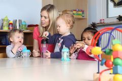 Eine Erzieherin sitzt mit drei Kindern am Tisch