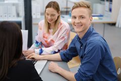 Zwei junge Leute sitzen zusammen am Tisch und lächeln.