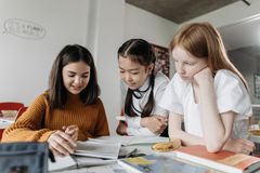 Drei Schülerinnen sitzen am Tisch und schauen gemeinsam in Unteralgen. 