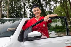Mitarbeiterin der Caritas steht an ihrem Dienstfahrzeug