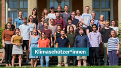 Das Team von co2online seht im Sommer vor einem Haus und posiert für ein Foto 