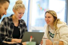 Eine Frau und ein Mädchen sitzen an einem Tisch, umgeben von Papieren und Notizen. Sie sind  am arbeiten, aber lachen auch gemeinsam.