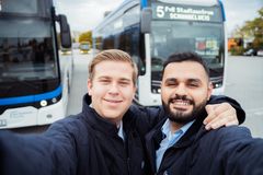 Zwei Azubis zur Fachkraft im Fahrbetrieb vor den Bussen, bereit, in ihre Schicht zu starten und den öffentlichen Verkehr zu unterstützen.