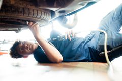 Azubi zum Kfz-Mechatroniker führt Reparaturen an einem Auto durch, während er unter dem Fahrzeug liegt – praxisorientierte Ausbildung in Fahrzeugtechnik.