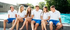 Ein Bild von mehreren Kollegen aus dem Freibad, die gemeinsam am Beckenrand sitzen und lachen. 