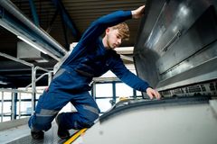 Ein Auszubildender zum Kfz-Mechatroniker für Nutzfahrzeuge arbeitet konzentriert an einem Linienbus in der Werkstatt. Mit Werkzeug in der Hand prüft er die Technik – ein Blick hinter die Kulissen der Ausbildung, bei der handwerkliches Geschick und technisches Know-how gefragt sind.