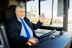 Ein Busfahrer am Steuer seines Busses winkt einem anderen Busfahrer. 