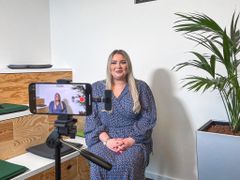 glückliche Frau, die in die Handykamera, befestigt an einem Stativ, lächelt
