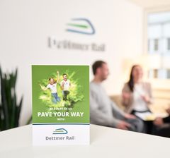 Im Vordergrund ein Ausbildungsflyer, im Hintergrund zwei Mitarbeitende