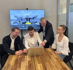 Mitarbeiter zeigt zwei Kollegen und einer Kollegin etwas am Notebook