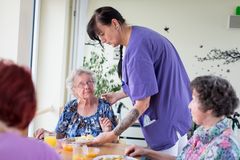 Eine Pflegefrau verteilt das Essen an eine ältere Dame.