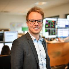 Mann im Anzug in modernem Büro, schaut freundlich in die Kamera