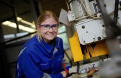 Auszubildende in blauer Schutzkleidung an einer Werkmaschine