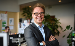 Mann im Anzug mit Brille lächelt in einem modernen Büro