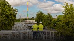 Zwei Männer der inetz, mit Bauhelm, stehen auf einem Gerüst und schauen Richtung Schornstein der eins energie Sachsen