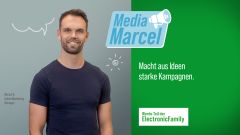 Lächelnder Mann ìn dunklem T-Shirt vor grauem Hintergrund, daneben Text 'Media Marcel - Macht aus Ideen starke Kampagnen.' 