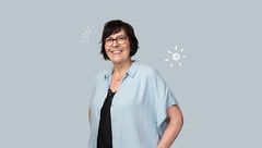 Lächelnde Frau mit weißer Bluse vor grauem Hintergrund