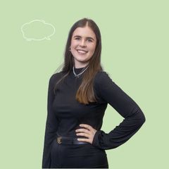 Frau mit langen braunen Haaren trägt ein schwarzes langärmeliges Oberteil und schwarzen Gürtel, steht vor hellgrünem Hintergrund mit Sprechblase.