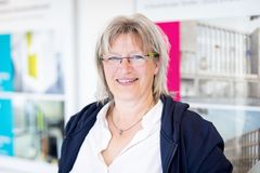 Lächelnde Frau mit kurzen, blonden Haaren und Brille, die bei der Stadt Elmshorn arbeitet. 