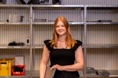 Eine junge Frau steht in einem Lager und lächelt freundlich