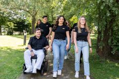 Eine Gruppe junger Menschen in schwarzen evm-Tshirts geht auf einem Weg und 