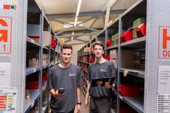 Zwei junge Männer stehen in einem Lager und lächeln freundlich