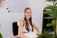 Eine junge Frau sitzt an einem Schreibtisch und lächelt freundlich