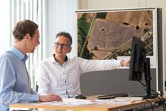 Zwei Männer sitzen vor einem Computer und unterhalten sich.