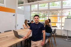 Ein junger Mann mit dunklen Haaren lächelt freundlich.