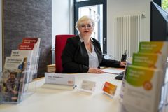 Eine Frau sitzt an einem Schreibtisch und lächelt freundlich