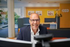 Ein Mann sitzt an einem Schreibtisch und lächelt freundlich