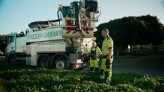Weißer Saugwagen mit blauer Aufschrift „FBG Der Fischereihafen“, zwei Arbeiter in neongelber Arbeitskleidung.